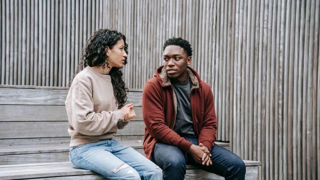 Unsatisfied multiethnic couple having conversation on stairs